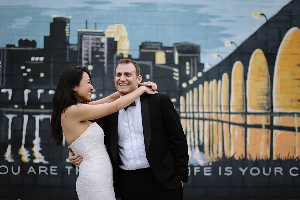 newlyweds in front of greetings from minneapolis mural