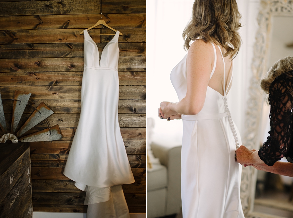 wedding dress hanging on barnwood wall; bride being buttoned into dress