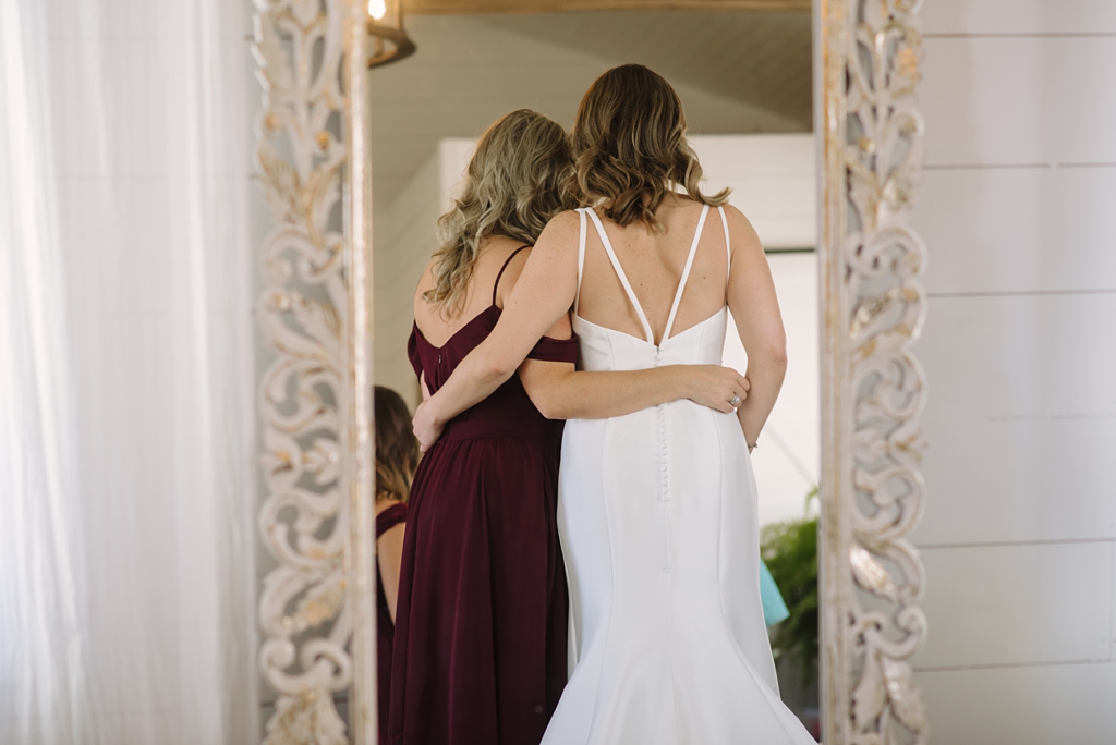 reflection from behind of bride embracing bridesmaid
