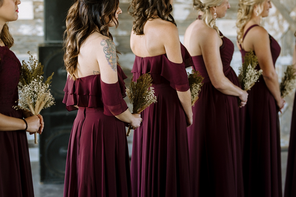 detail of bridesmaids in burgandy dresses with rustic bouquets