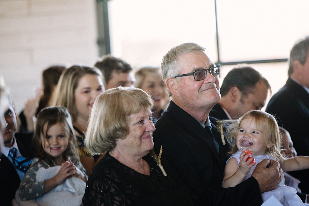 bride's parents hold flower girl while watching serenity hills minnesota ceremony