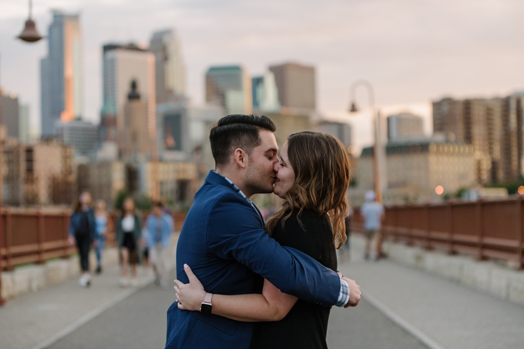 newly engaged couple kisses in front of minneapolis skyline