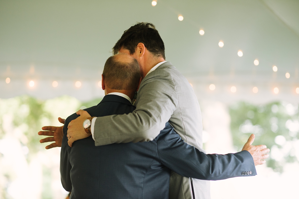 groom hugs dad at backyard wedding reception