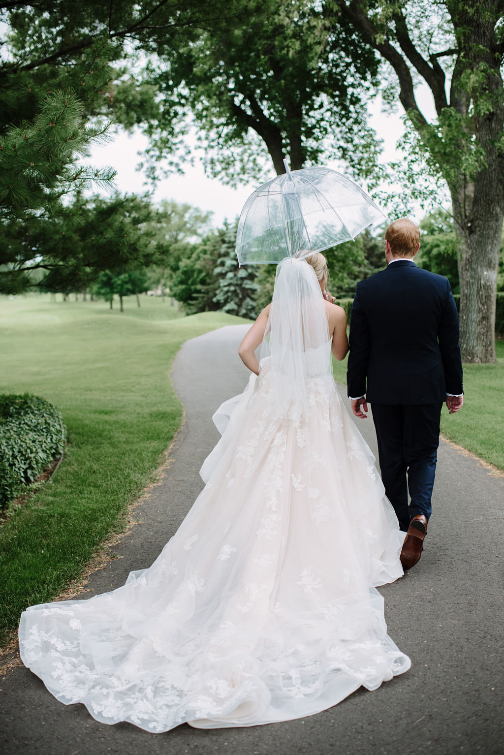 bride and groom walk away together under umbrella