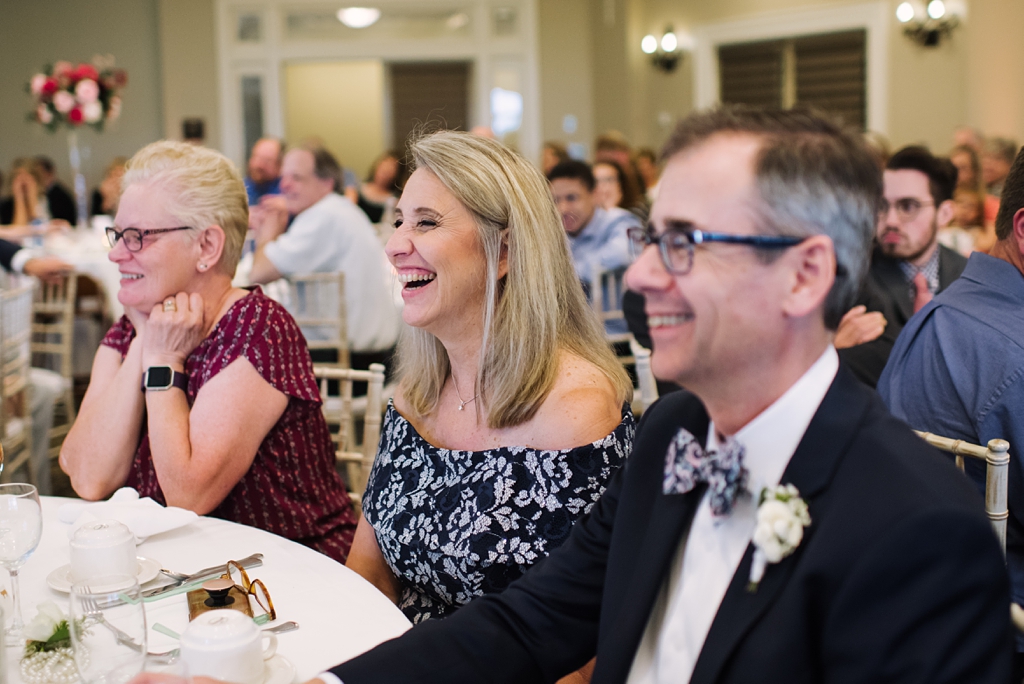 bride's parents laugh during wedding speeches