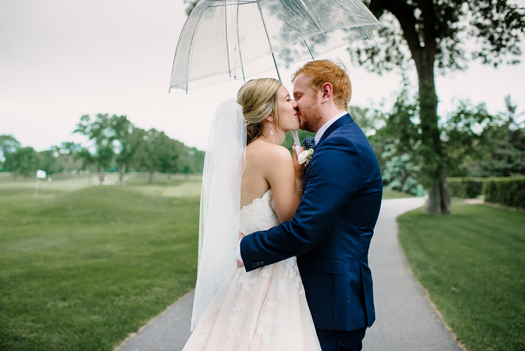 newlyweds kiss under clear umbrella