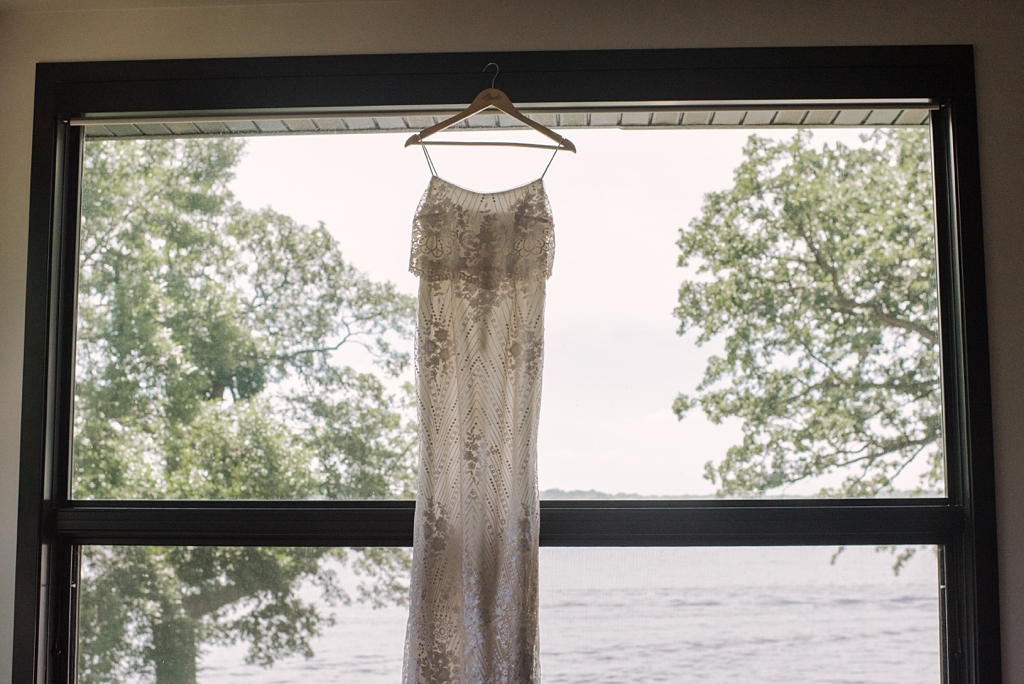 wedding dress hanging in window facing lake