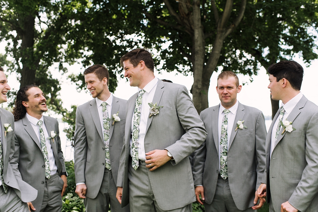 groom talking with groomsmen at lakeside minnesota wedding