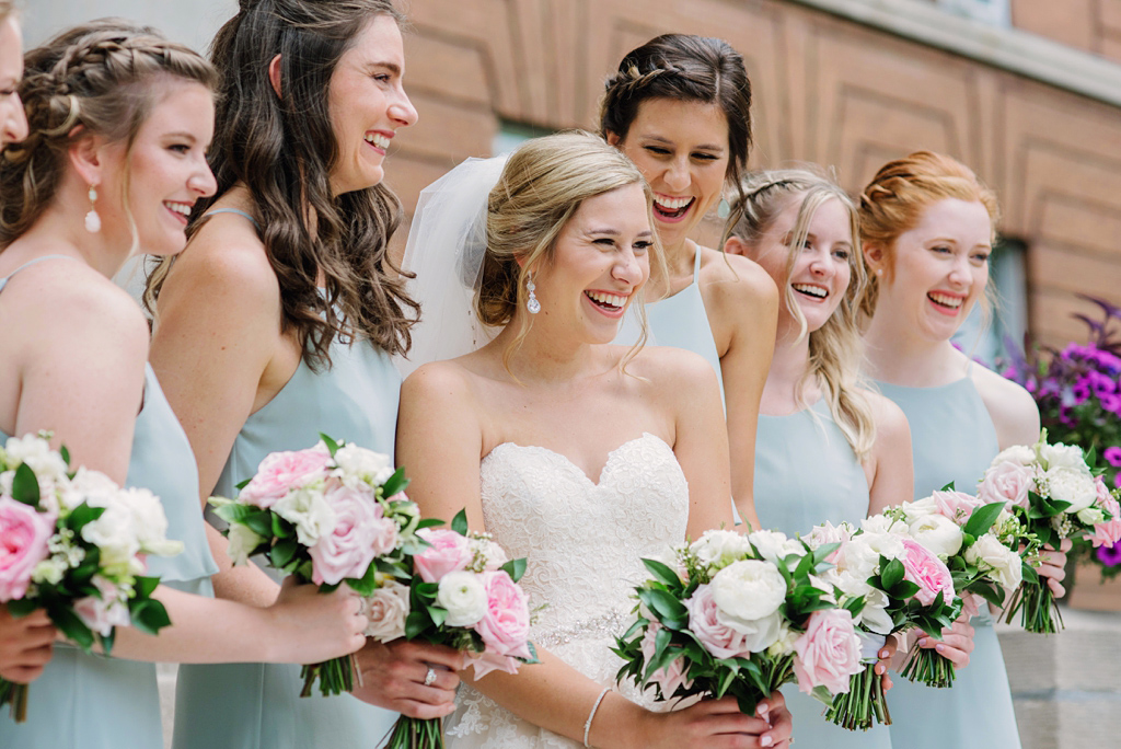 bride and bridesmaids laughing on church steps