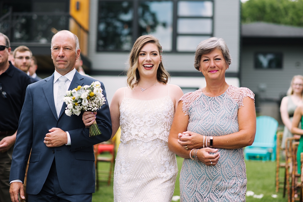 bride escorted down aisle by parents at backyard wedding