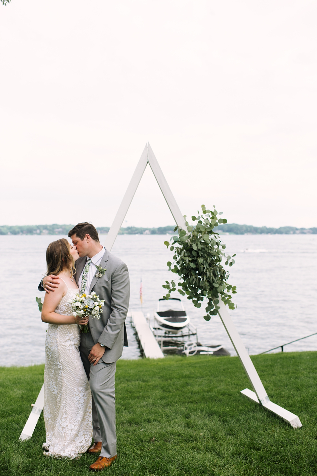 newlyweds kiss by wedding a-frame lakeside minnesota