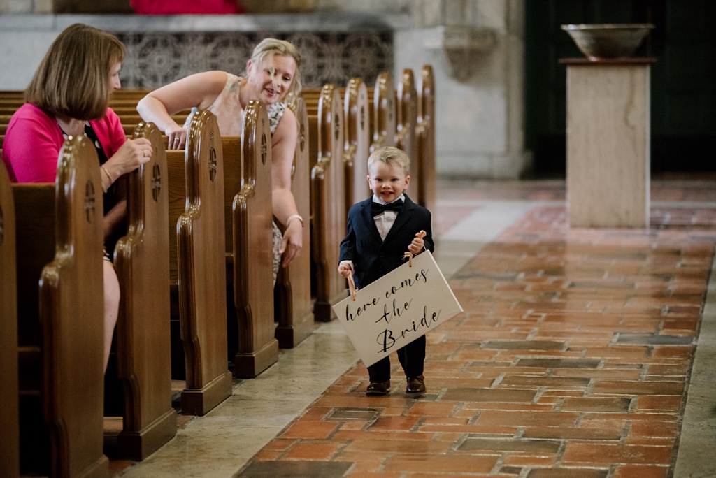 ring bearer carrying sign down aisle