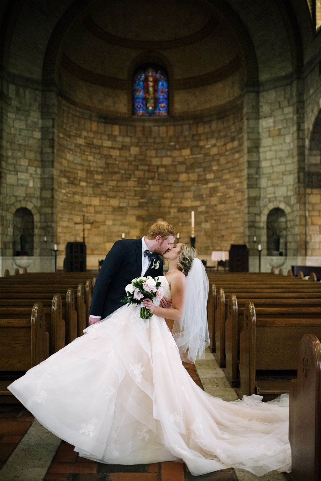 groom dips and kisses bride in chapel