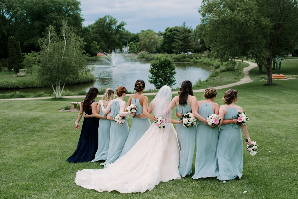 bridal party arm in arm on grassy lawn