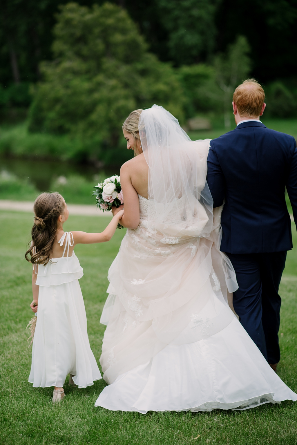 bride and groom walk with flower girl