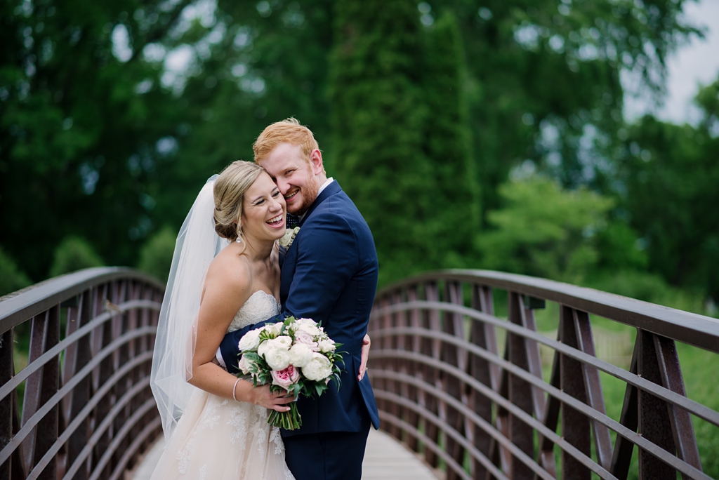 newlyweds laugh and embrace on walking bridge