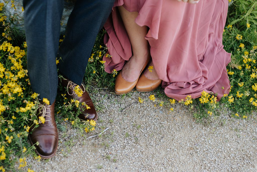 detail of couple's feet on gravel path with yellow flowers