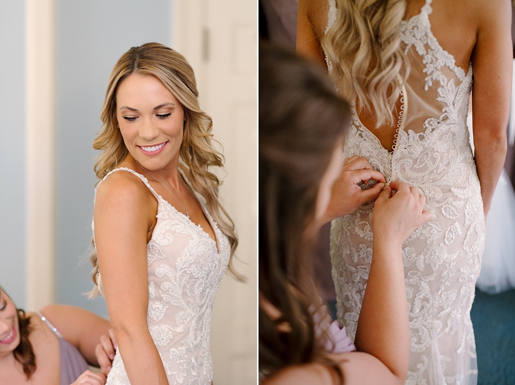 bride smiling over her shoulder at bridesmaid buttoning dress