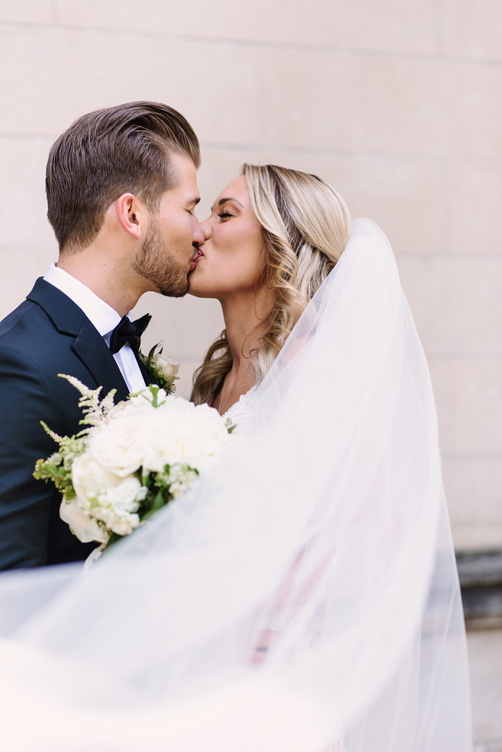 bride and groom kiss with sweeping veil