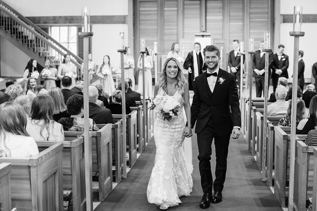 newly married couple walk together down aisle