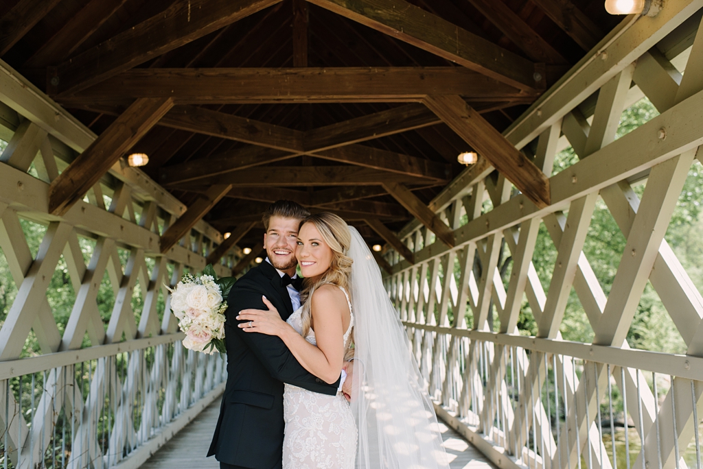 bride and groom embracing on a covered bridge