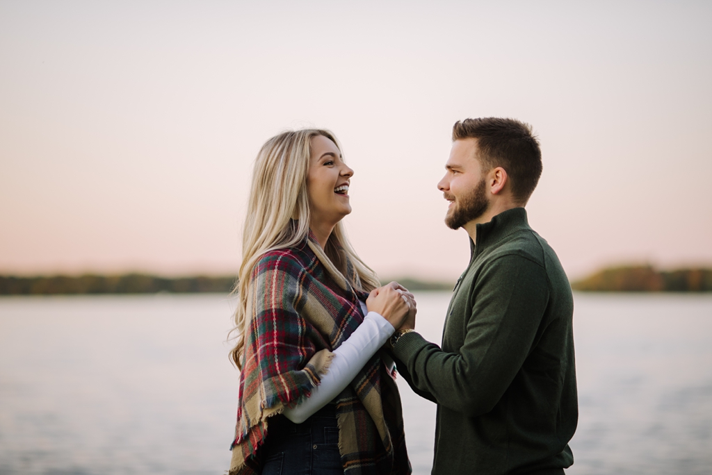 engaged couple laughing at dusk lakeside