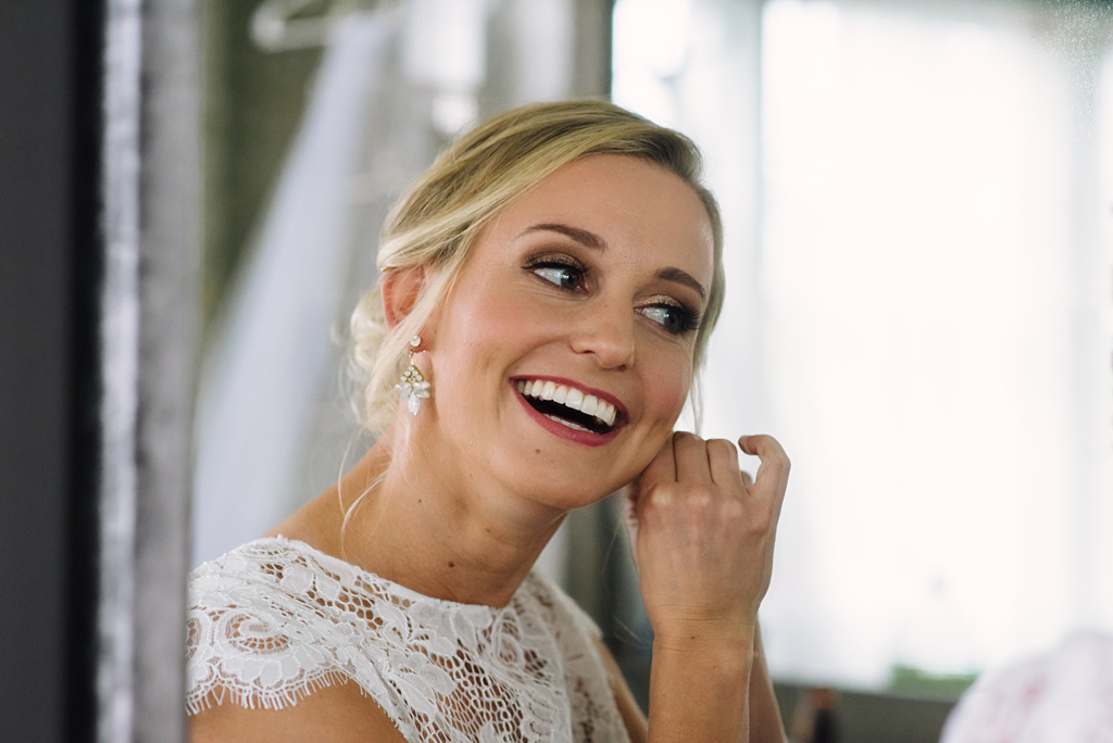 bride smiles while putting in earrings