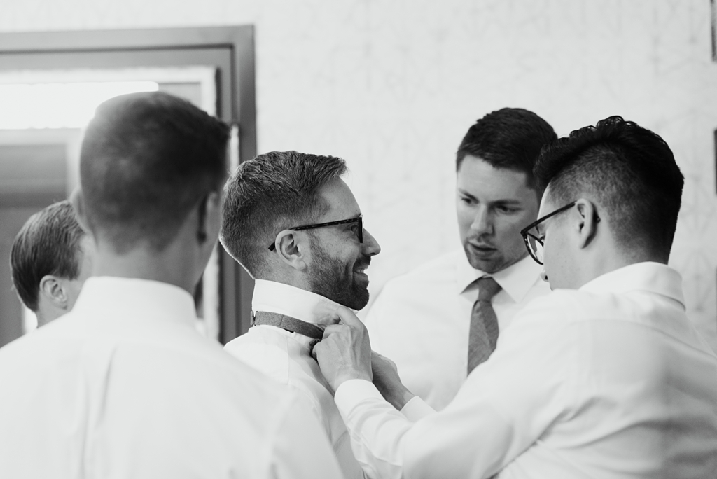 groomsmen help groom with bowtie