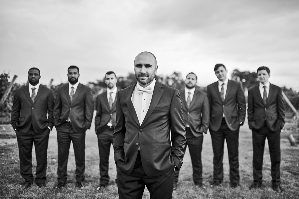 groom in foreground with groomsmen in background with dramatic black and white