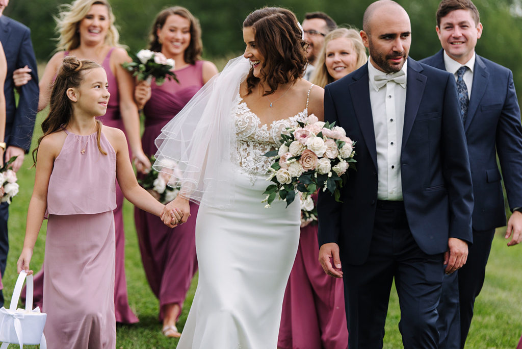 wedding party walking with bride holding hands with flower girl