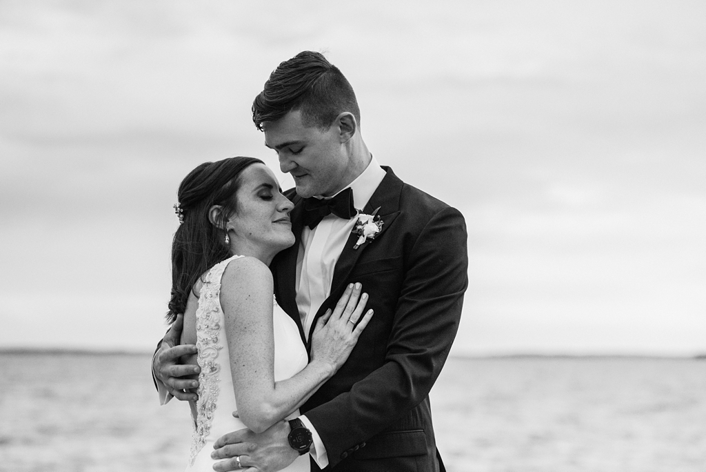 newlyweds embrace lakeside in black and white