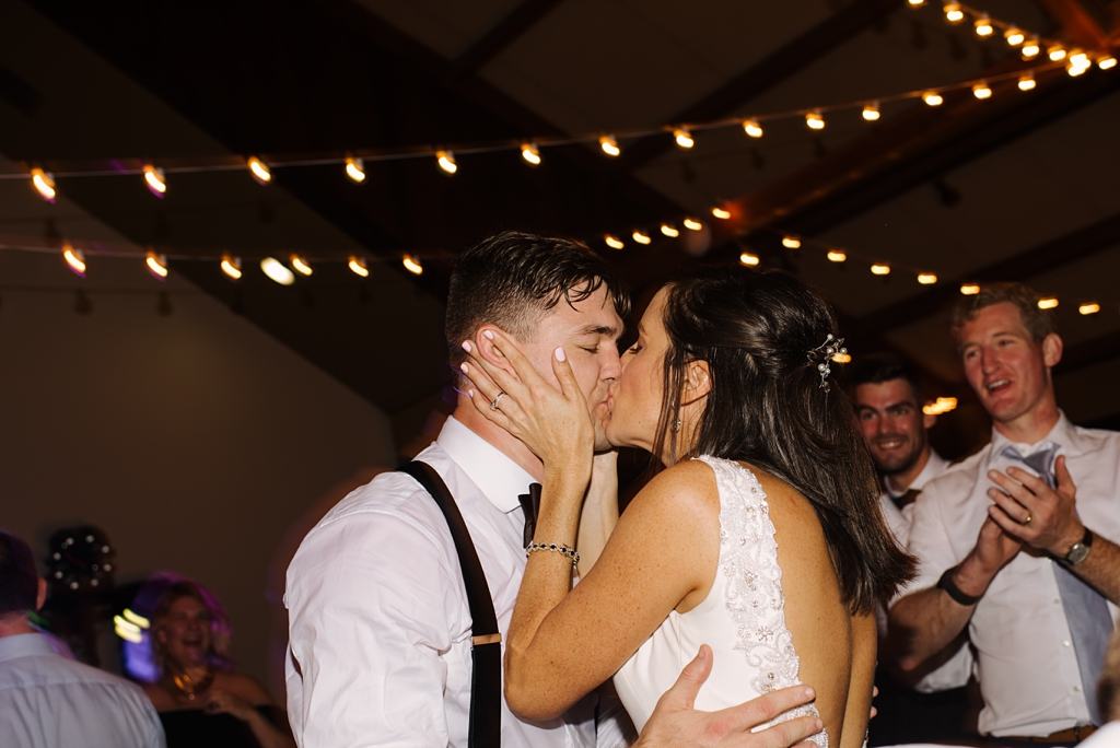 bride and groom kiss on dance floor at lodge wedding reception
