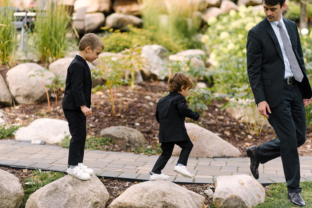 boys in suits jumping on rocks at lodge wedding