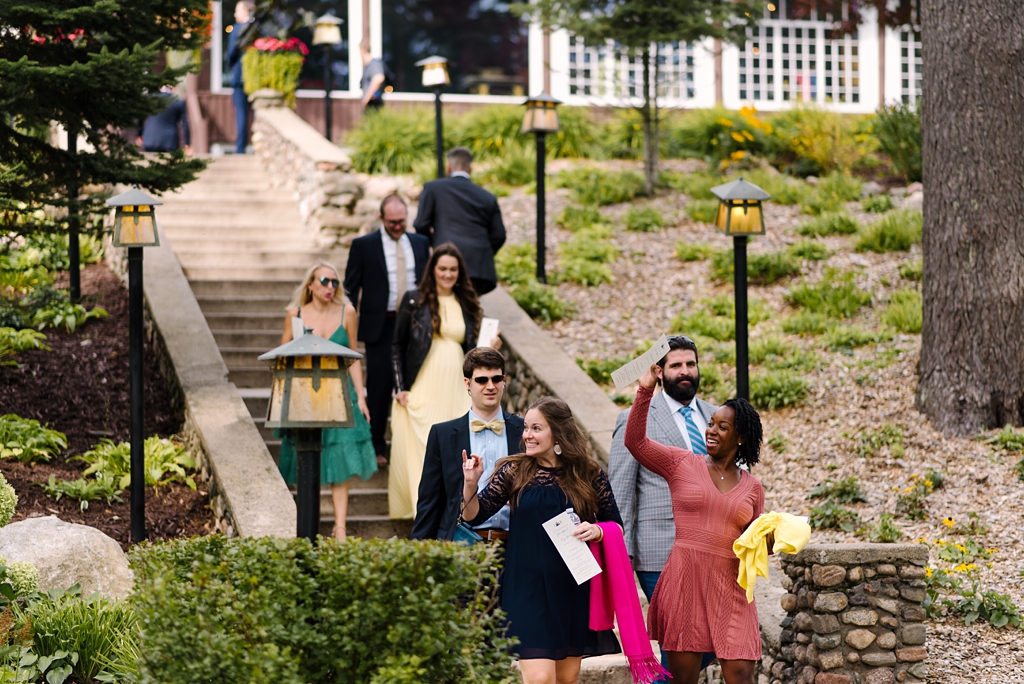 wedding guests waving as they come down stone stairs
