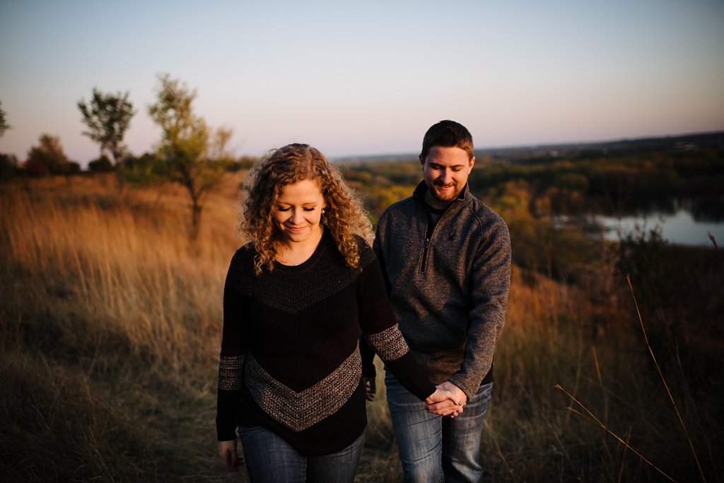 couple walking in a field holding hands in a field in Minnesota
