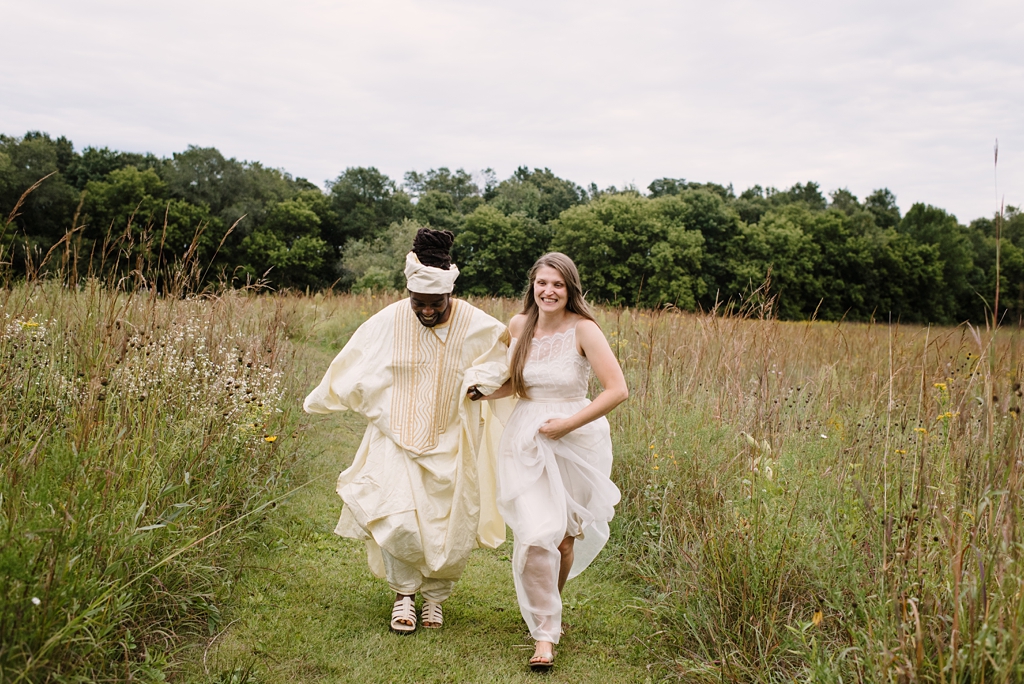 bride and groom run together through prairie