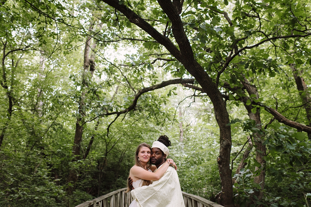 newlyweds embrace under green trees after campground wedding