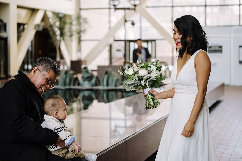 bride with bouquet and baby guest at courthouse wedding