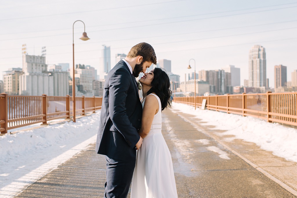 newlyweds on stone arch bridge in winter