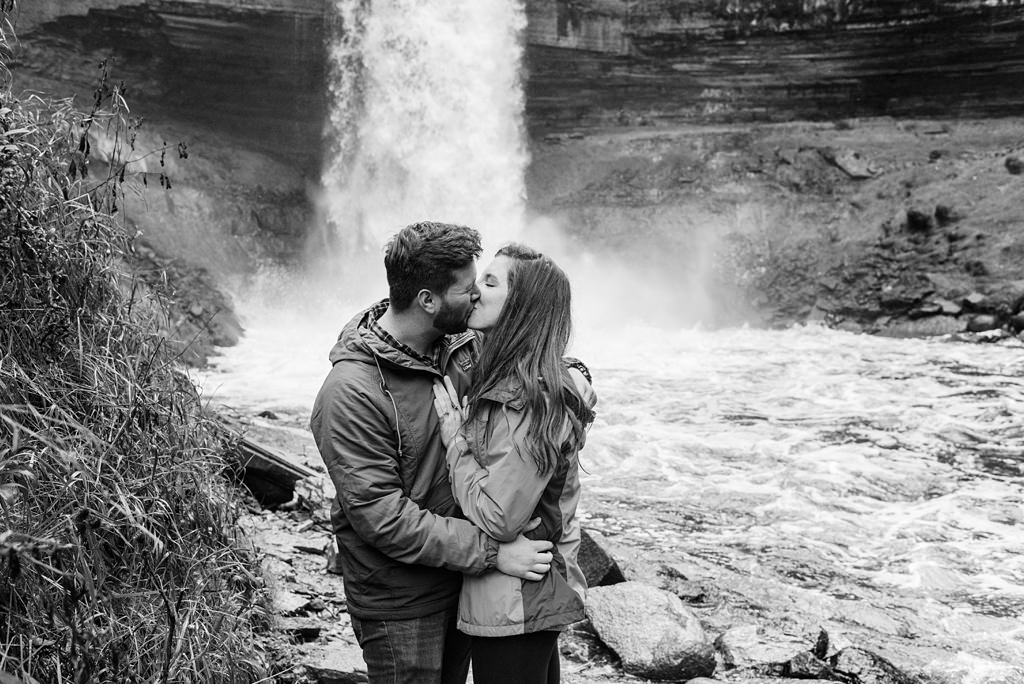 newly engaged couple kisses at minnehaha falls in minneapolis mn
