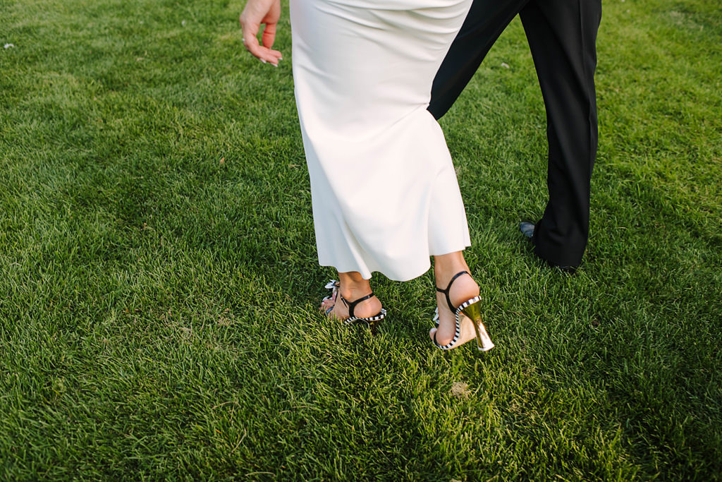 detail of feet as bride and groom walk through grass