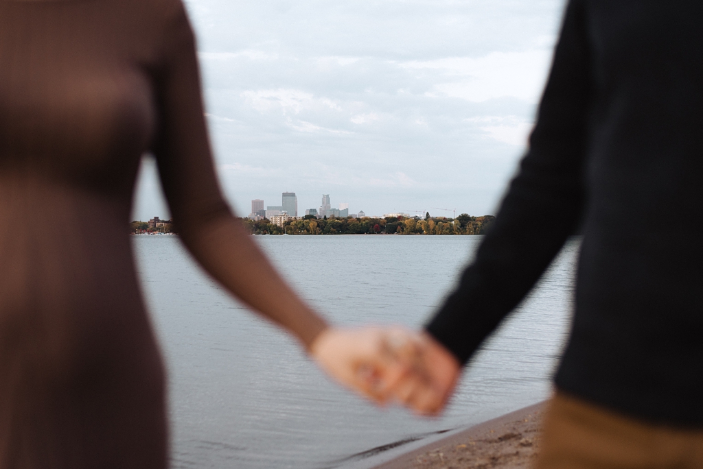 minneapolis sky line in focus behind couple holding hands