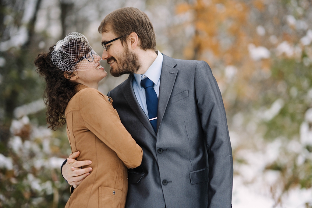 newlyweds kissing in snowy minnesota nature preserve