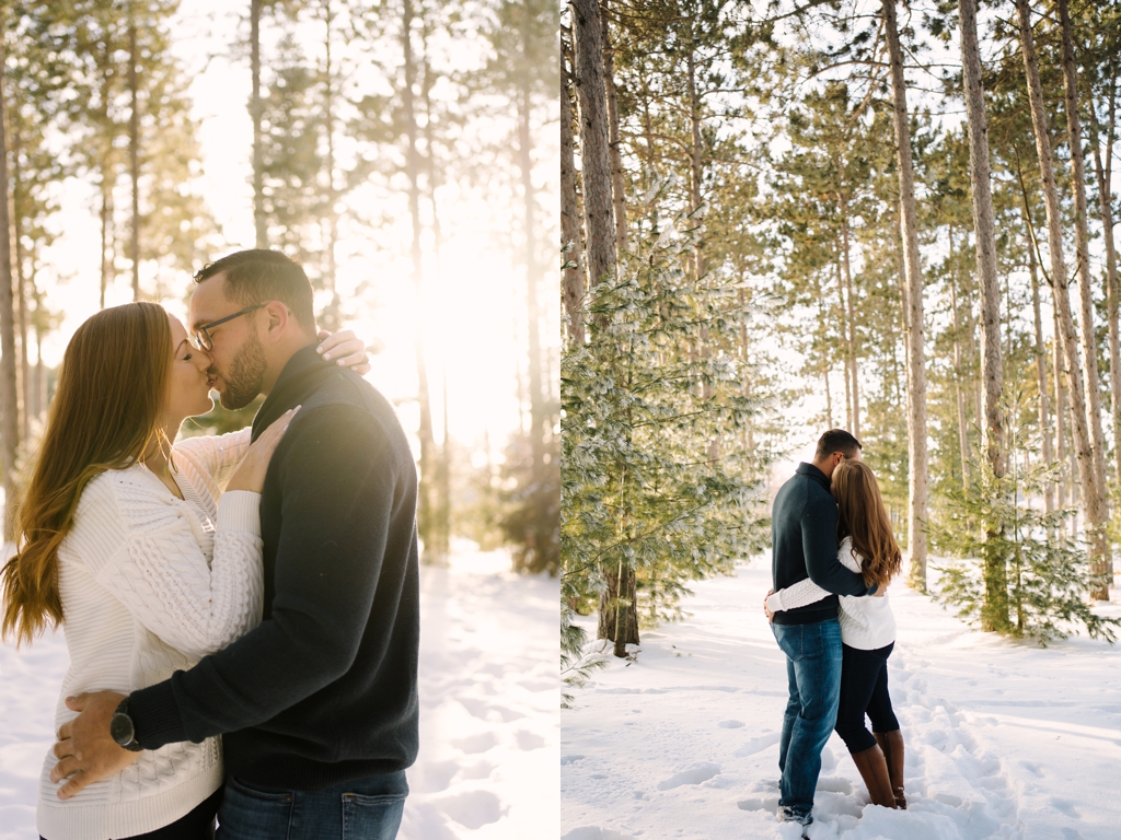 engaged couple kissing in snow at sunset with trees