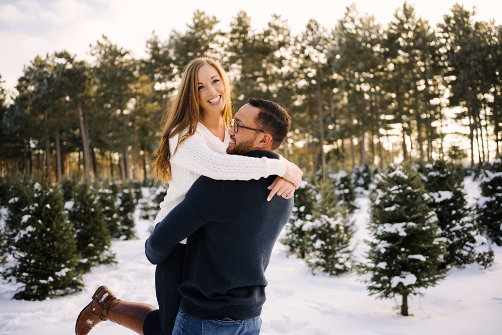 smiling couple in snowy tree farm