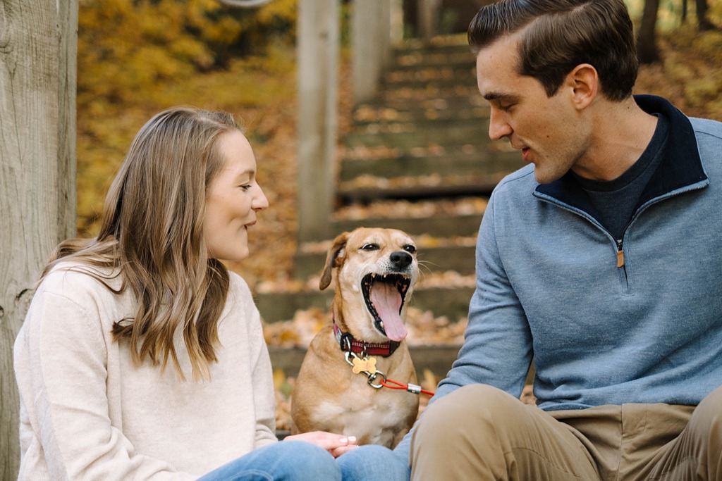 couple sitting on stairs with yawning dog