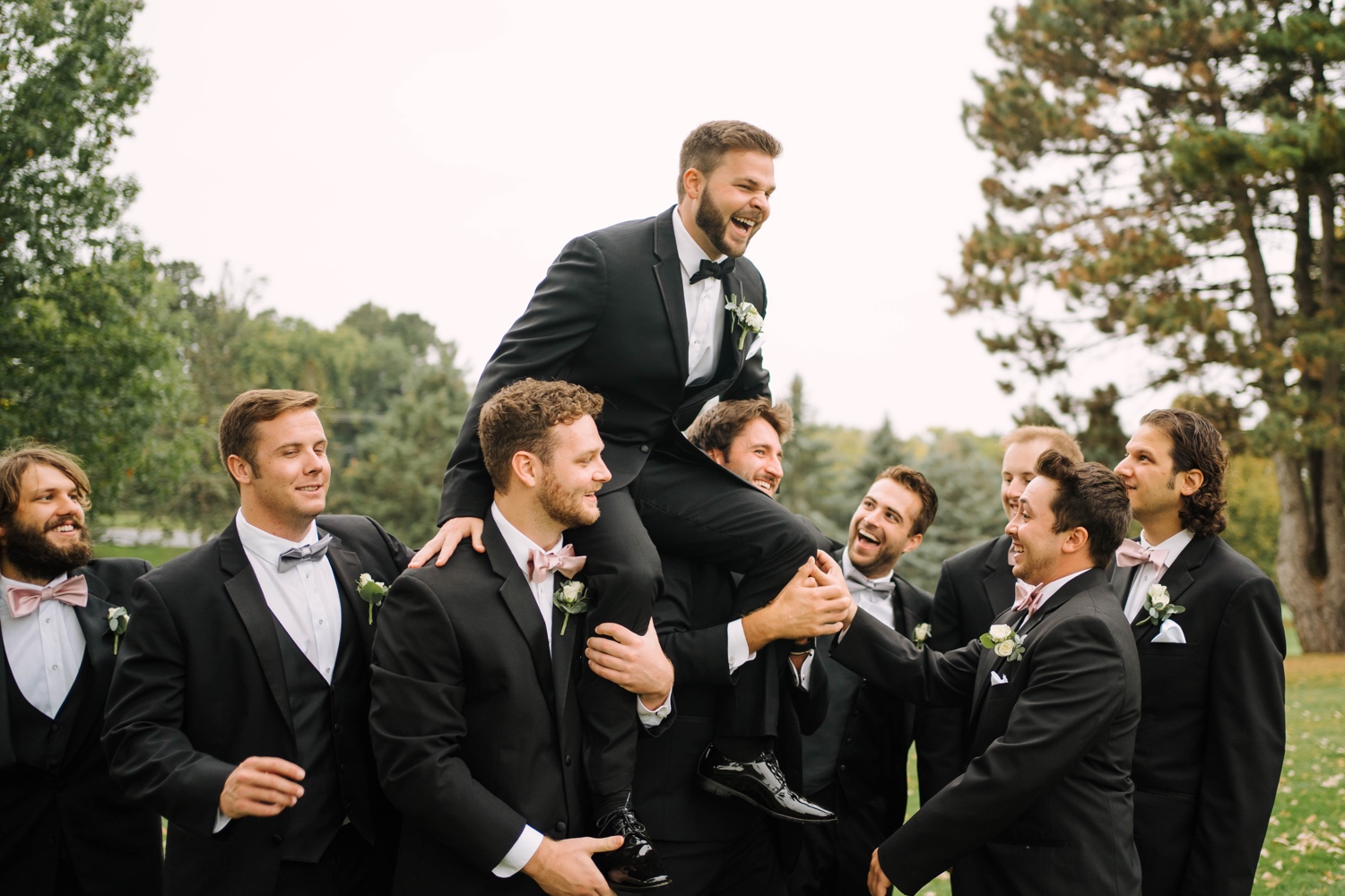 groomsmen lifting laughing groom outside