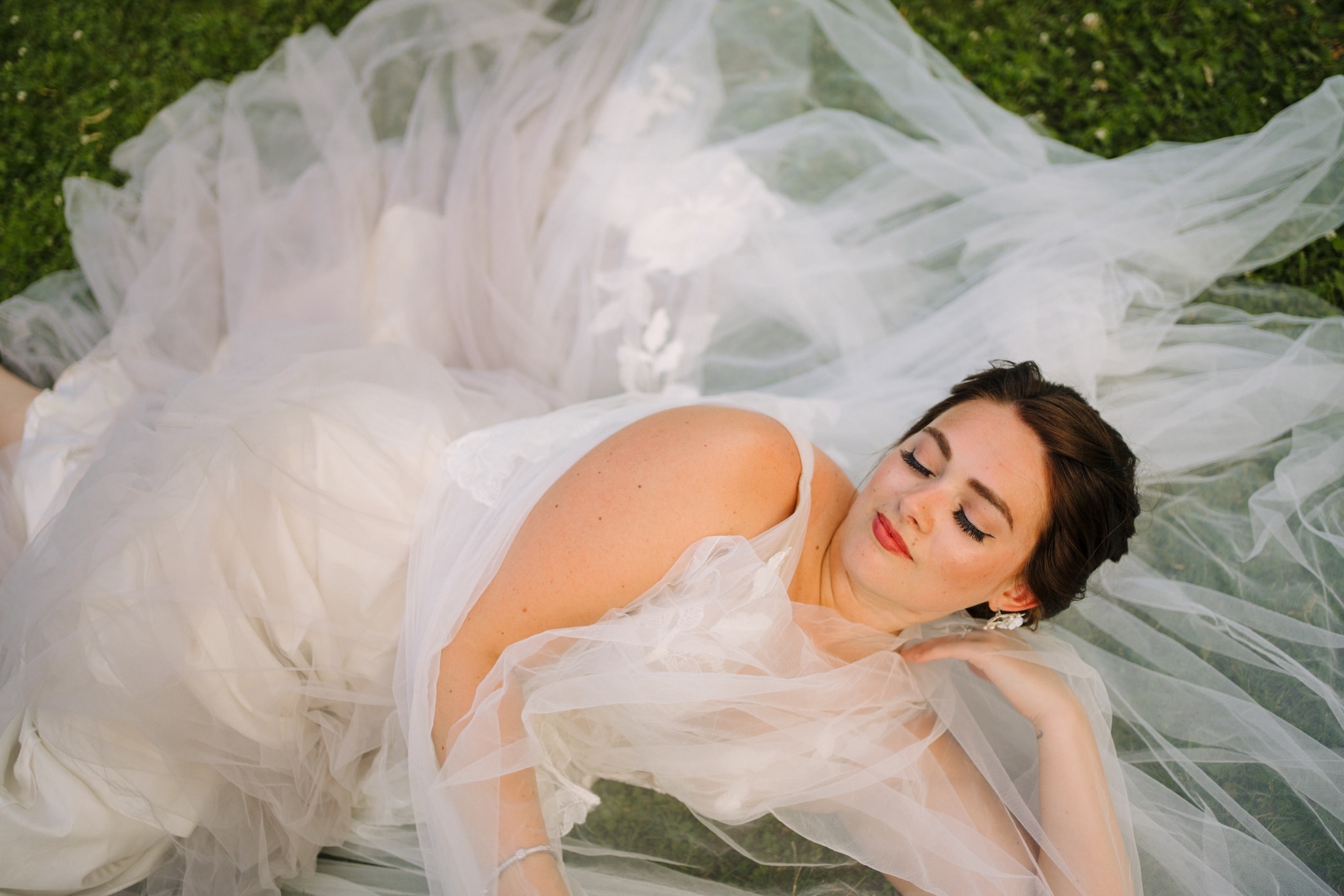 bride lounging in dress in grass field