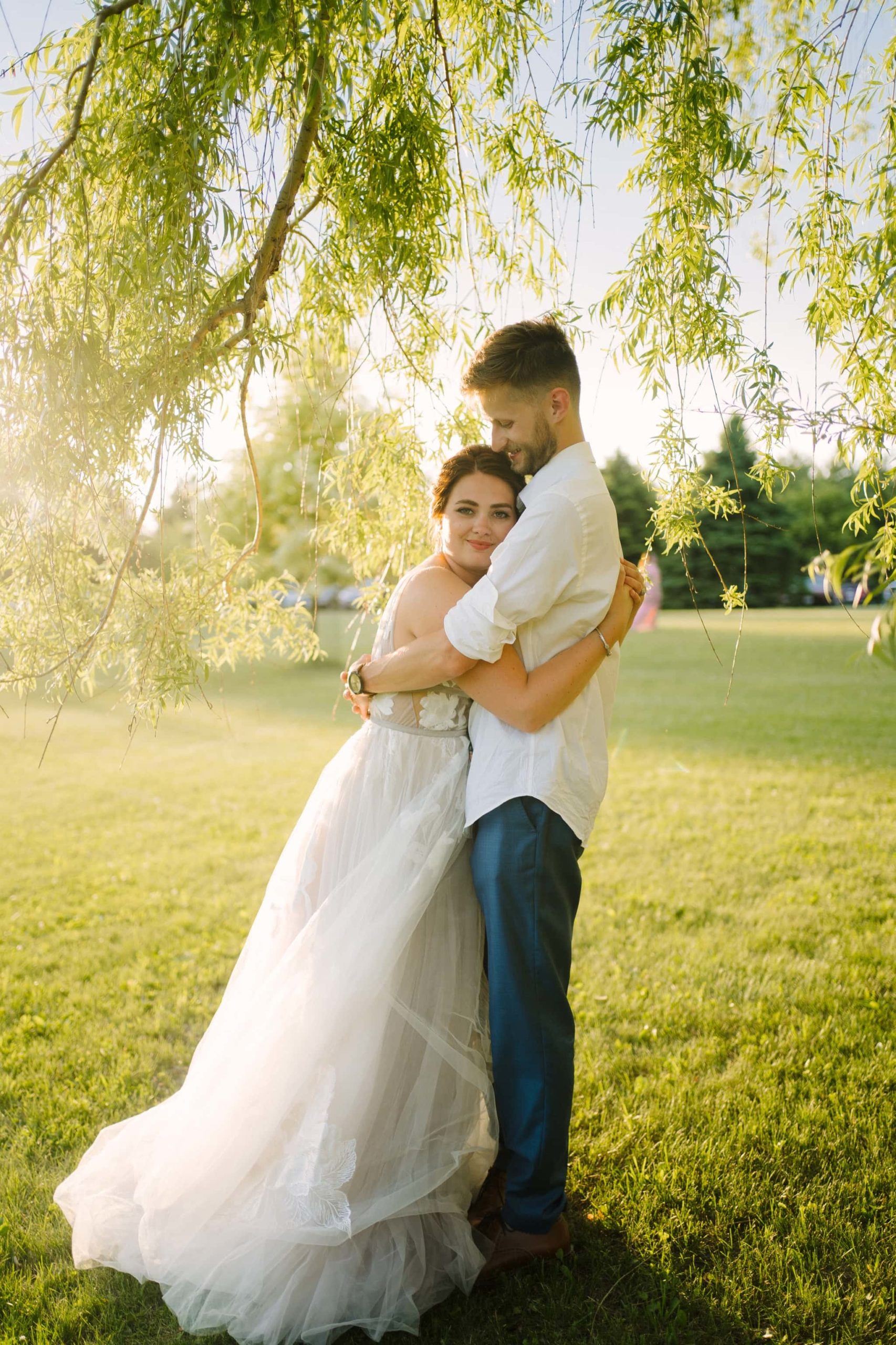 bride and groom hug under willow tree