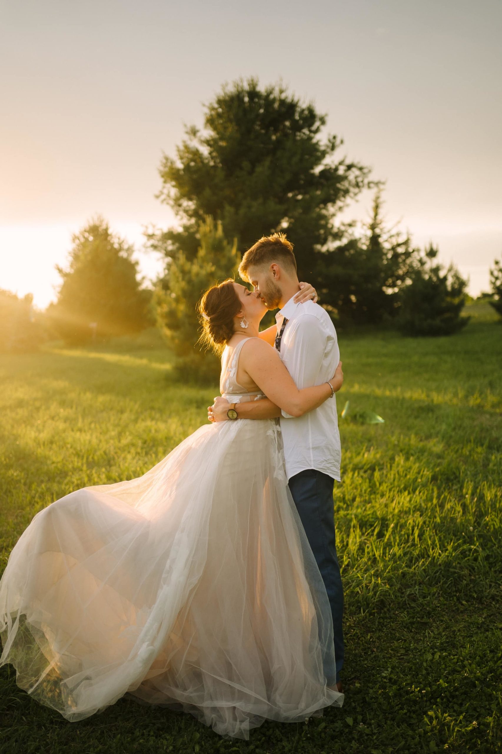 newlyweds kiss in green field with foot pop